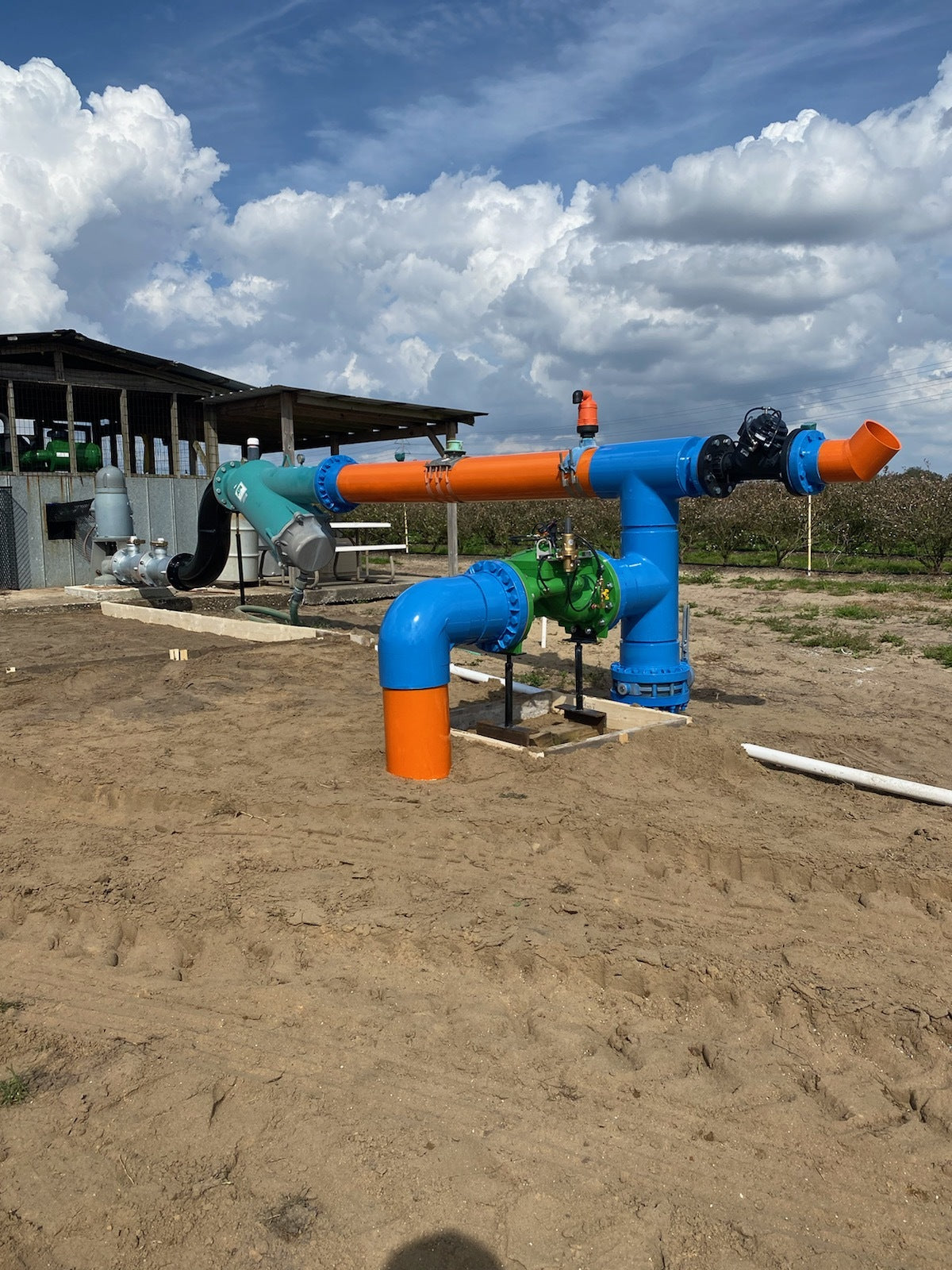 Large blue and orange pipes on a dirt ground with a cloudy sky.